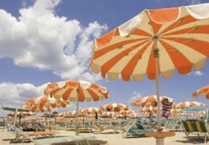 een stel parasols en stoelen op een strand bij Hotel Bonaria in Rimini