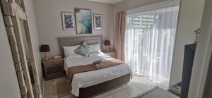 a bedroom with a bed and a large window at The Coelacanth Guest House And Beach Thyme Self Catering in Kiddʼs Beach