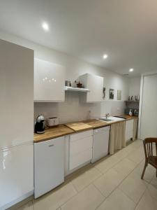 a kitchen with white cabinets and a wooden counter top at LE FIGUIER in Cabestany