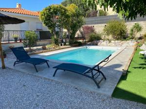 a swimming pool with two blue chairs next to it at LE FIGUIER in Cabestany