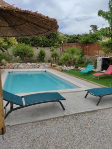 a swimming pool with an umbrella and two chairs at LE FIGUIER in Cabestany +2 photos