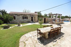 a stone house with a table and chairs in a yard at Villa Palace in Donji Zemunik