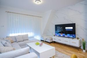 a living room with a white couch and a flat screen tv at Lux Sara Apartments in Visoko