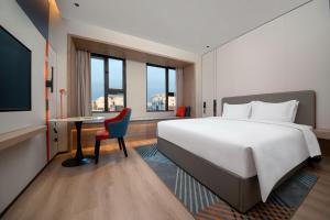 Holiday Inn Express Suzhou Shihu University Town في سوتشو: غرفة في الفندق بها سرير ومكتب وتلفزيون