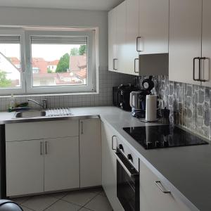 cocina con armarios blancos, fregadero y ventana en Haus Castellblick 3, en Ballrechten