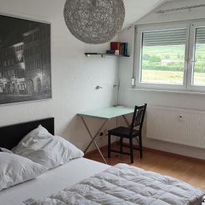 1 dormitorio con escritorio, silla y cama en Haus Castellblick 3, en Ballrechten