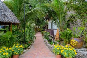 a walkway in a garden with flowers and a building at Bình An Village in Vĩnh Long