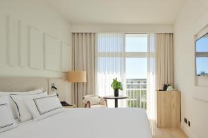 a bedroom with a white bed and a large window at Meliá Lloret de Mar in Lloret de Mar