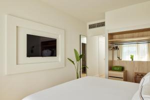 a bedroom with a white bed and a tv on a wall at Meliá Lloret de Mar in Lloret de Mar