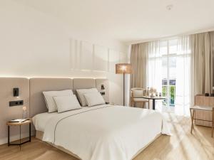a white bedroom with a large white bed with white pillows at Meliá Lloret de Mar in Lloret de Mar
