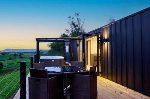 a black house with a table and chairs on a deck at Umry-Calm Farm Stays in Feeny