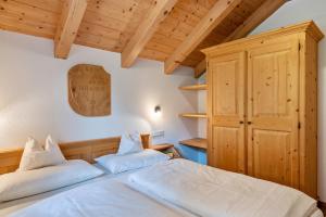 two beds in a bedroom with wooden ceilings at Kranebitterhof Apt Enzian in Valdaora