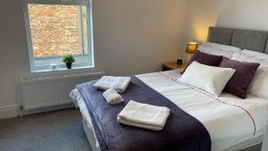a bedroom with a large bed with two towels on it at CityGo Apartments Queens Wellington in Belfast