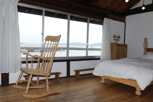 einen Schaukelstuhl aus Holz in einem Schlafzimmer mit einem Bett in der Unterkunft Womb Guesthouse Kojima -Uminomieru ie- - Vacation STAY 95107v in Tamano