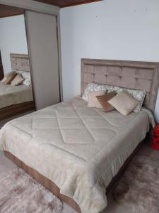 a bedroom with a large bed with pillows and a mirror at Pousada Paraíso dos Canyons in Praia Grande
