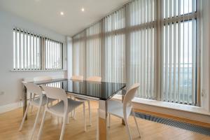 comedor con mesa negra y sillas blancas en Roomspace Serviced Apartments - The Courtyard Penthouse, en Londres