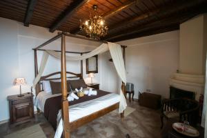 - une chambre avec un lit à baldaquin et un lustre dans l'établissement Enastron Guesthouse, à Palaios Panteleimonas