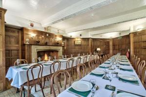 una sala da pranzo con tavoli, sedie e camino di Caer Beris Manor By Group Retreats a Builth Wells