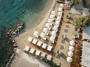 an aerial view of a beach with white umbrellas and the ocean at Angsana Corfu Resort & Spa in Benitses