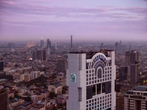 a tall white building with a logo on it in a city at Banyan Tree Bangkok in Bangkok