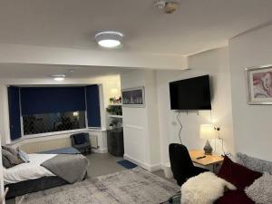 a bedroom with a bed and a desk and a television at Impressive Large StudioWoodford in Woodford Green