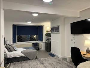 1 dormitorio con 1 cama y TV de pantalla plana en Impressive Large StudioWoodford, en Woodford Green