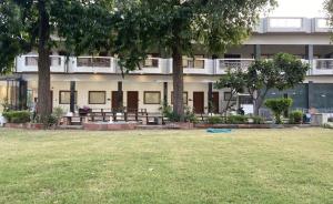 a building with trees and a field in front of it at The Kedar Resort in Mathura