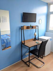 uma secretária e uma cadeira num quarto com uma parede azul em Belle chambre lumineuse dans appartement em Évry-les-Châteaux