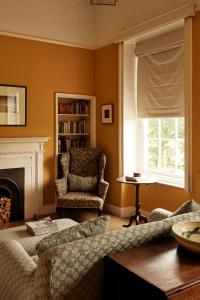 - un salon avec un canapé, une chaise et une fenêtre dans l'établissement Thirsk Hall South Wing, North Yorkshire, à Thirsk