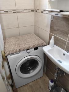 y baño pequeño con lavabo y lavadora. en SIESTA vendégház en Kiskunhalas