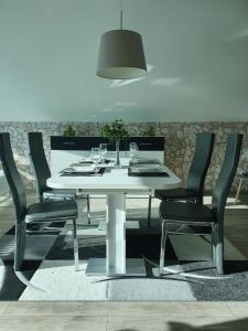 mesa de comedor blanca con sillas negras y lámpara en Ferienwohnung Mühlenhof, en Duderstadt