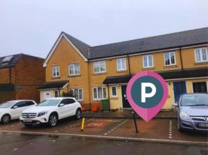 um parque de estacionamento com um letreiro cor-de-rosa em frente às casas em The Commuter's Lodge em Laindon
