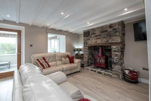 a living room with a couch and a stone fireplace at Neigwl View in Llanfihangel Bachellaeth