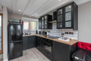 a kitchen with black cabinets and a black refrigerator at Neigwl View in Llanfihangel Bachellaeth +20 photos