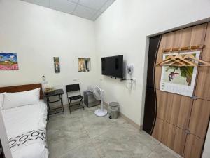 een slaapkamer met een bed, een bureau en een tv bij Happy B&B in Yuli