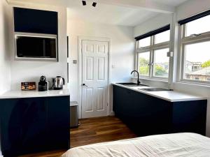 a kitchen with blue cabinets and a sink and a window at Cozy Studio near Regent’s Park N9 in London