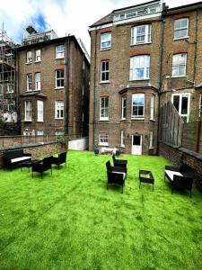 un groupe de bancs assis dans l'herbe devant un bâtiment dans l'établissement Cozy Studio near Regent’s Park N9, à Londres