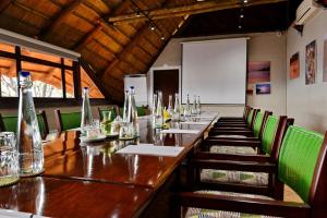 a long table in a restaurant with green chairs at Victoria Falls Safari Lodge in Victoria Falls