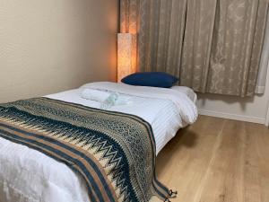 łóżko w pokoju z lampką i oknem w obiekcie 幸町HOUSE w Tokio