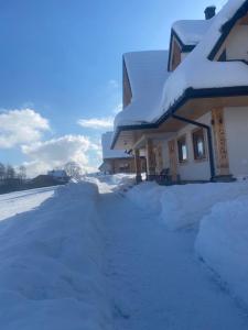 a house covered in snow with a driveway at Apartament Zielony by Homeprime in Bukowina Tatrzańska +9 photos