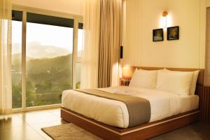 a bedroom with a large bed and a large window at Leaves Resort Vythiri Wayanad in Vythiri