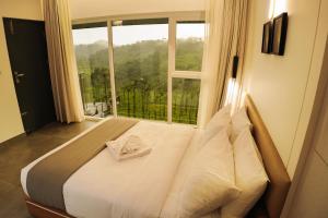 uma cama num quarto com uma grande janela em Leaves Resort Vythiri Wayanad em Vythiri