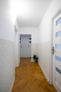ClickTheFlat Stawki Apart Rooms في وارسو: ممر فارغ بجدران بيضاء وارضيات خشبية