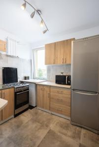 een keuken met houten kasten en een roestvrijstalen koelkast bij ClickTheFlat Stawki Apart Rooms in Warschau