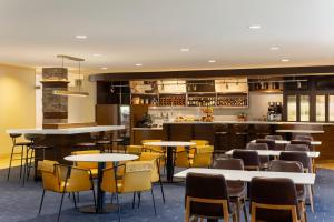 a restaurant with tables and chairs and a bar at Courtyard by Marriott Madison West / Middleton in Middleton