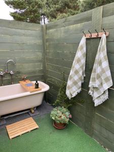 bañera junto a una valla de madera con una planta en White Croft Cottage en Ross