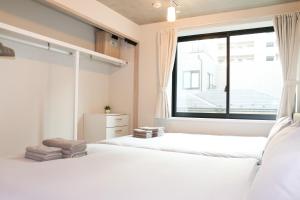 two beds in a bedroom with a large window at Seirai Asakusa Vacation Rental - 3 minutes from station in Tokyo