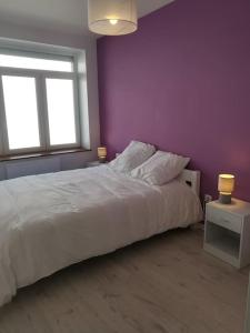 a bedroom with a white bed and a purple wall at Cocoon Bugiste : travail, sport ou détente in Hauteville-Lompnes