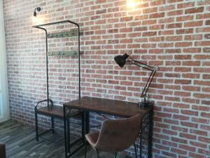 a desk with a lamp and a chair next to a brick wall at Cocoon Bugiste : travail, sport ou détente in Hauteville-Lompnes
