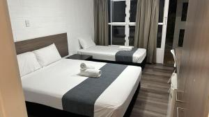 a hotel room with two beds with a towel on them at Townsville City Motel in Townsville